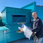 Claremont resident feeding cardboard into cardboard compactor